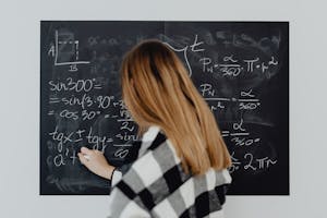 A woman writing mathematical equations on a blackboard, illustrating education and learning.