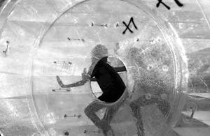 Black and white image of a person inside a transparent zorbing ball, creating a dynamic silhouette effect.