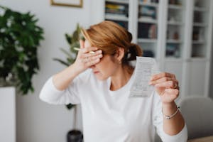 Woman experiencing stress while reviewing household expenses at home.